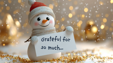 A cute, AI illustration of a snowman holding a sign that reads, "Grateful for so much", while golden snow falls around him.