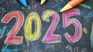Colourful chalk numbers drawn on a blackboard with pencil crayons in the background